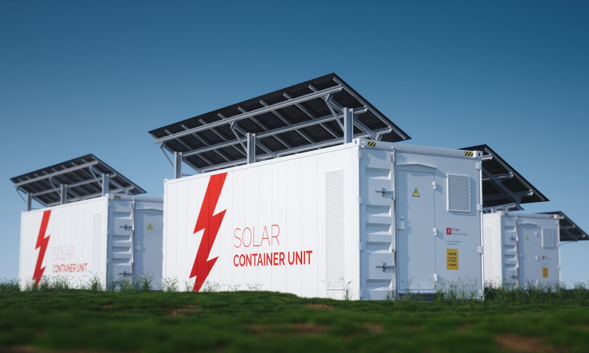 Rows of white solar container units topped with black solar panels, standing on green grass under a clear blue sky. Each container is labeled with a red lightning bolt and the words “SOLAR CONTAINER UNIT,” representing renewable energy storage powered by lithium-ion technology.
