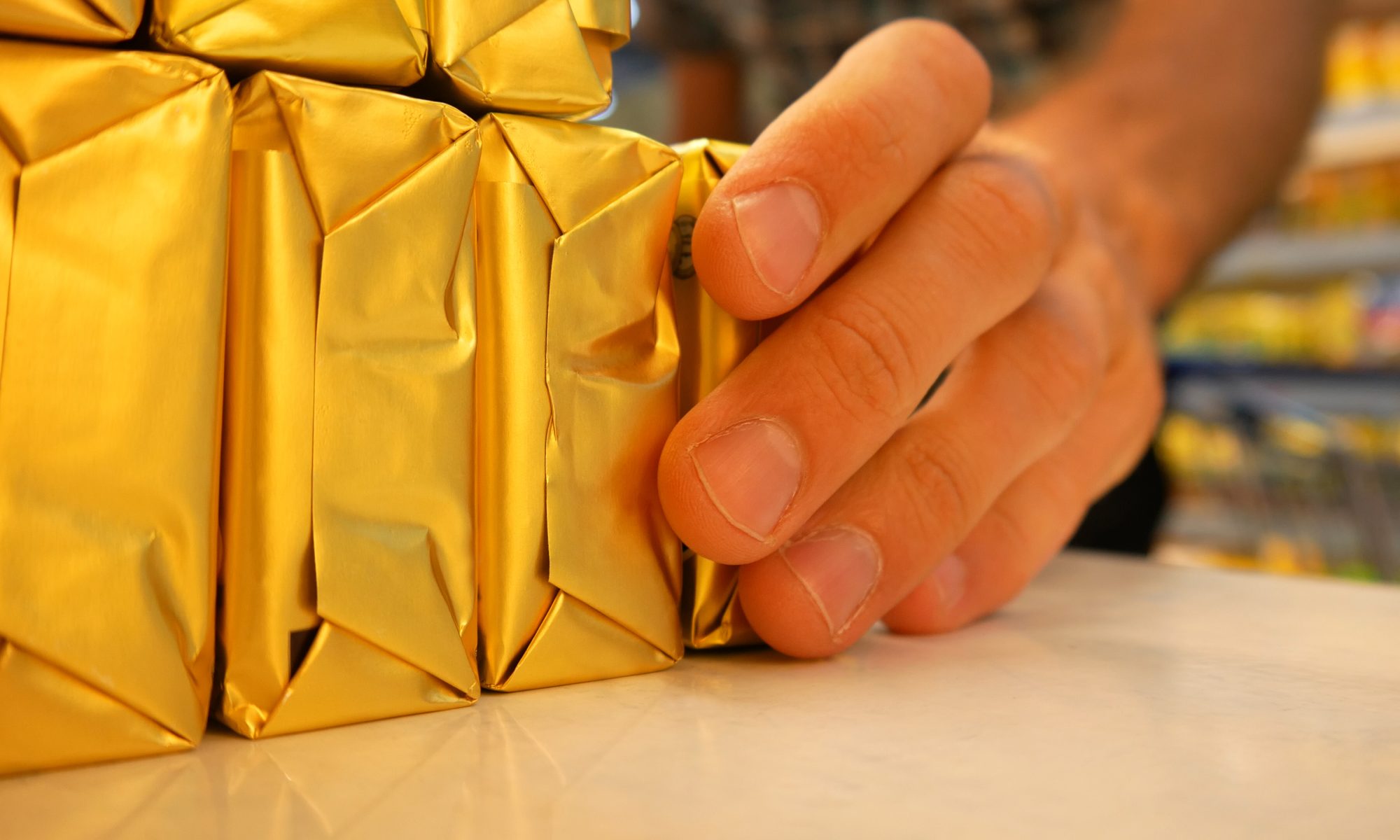 Many packagings of butter in a supermarket and a man with shopping trolley takes one