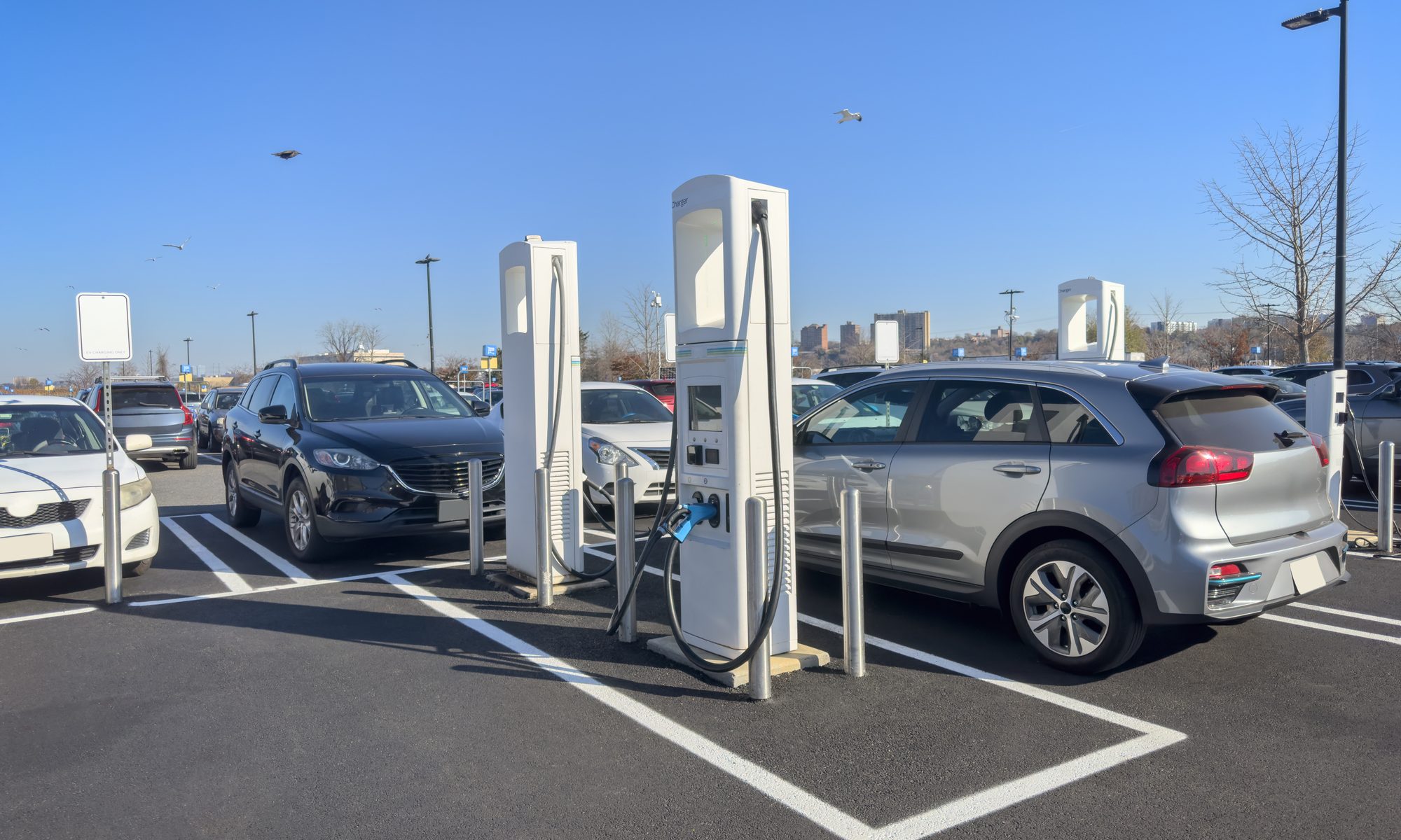 Electric vehicles charging at fast EV charging stations in a Walmart parking lot as the retailer expands its U.S. charging network.