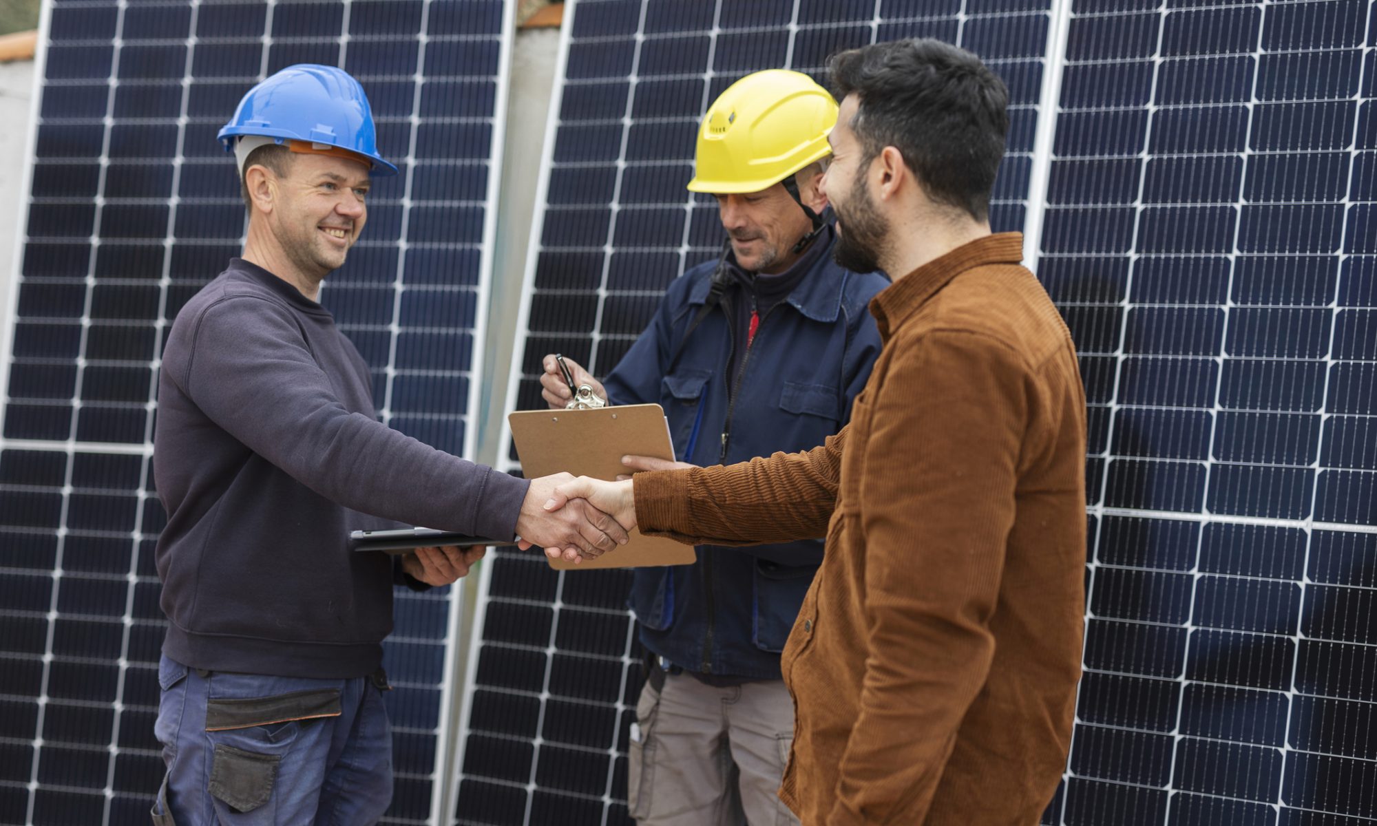 Solar installation professionals shake hands in front of large photovoltaic panels, signaling a business agreement in renewable energy and energy storage.