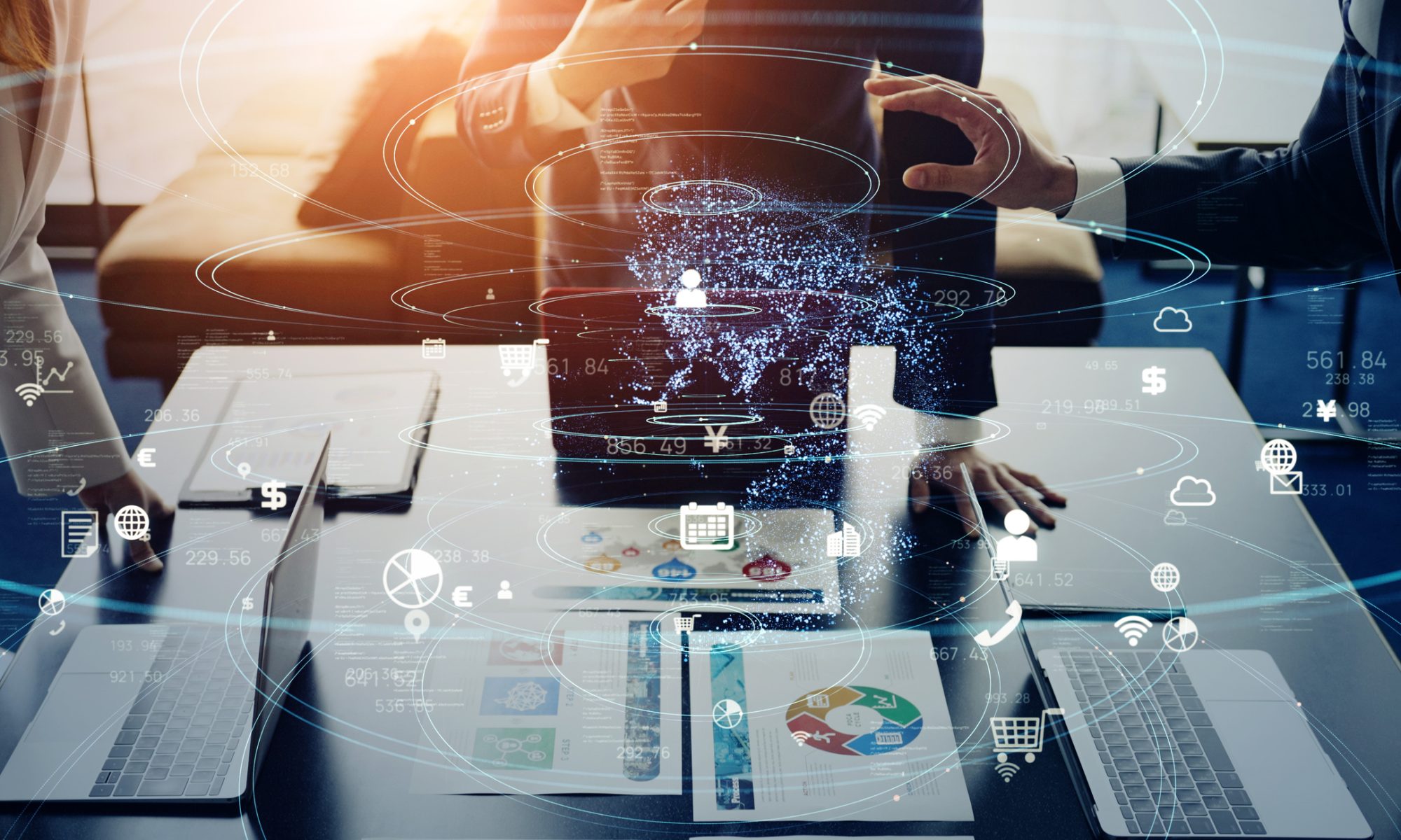 Business executives collaborate around laptops with digital data overlays representing cloud computing, analytics, and enterprise transformation.
