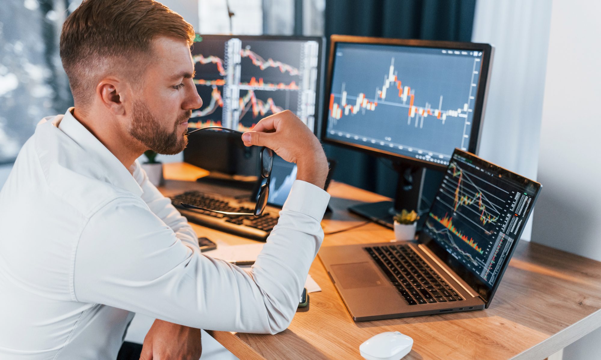 Trader analyzing live stock charts on multiple screens at a desk, reviewing intraday market movements and price action.