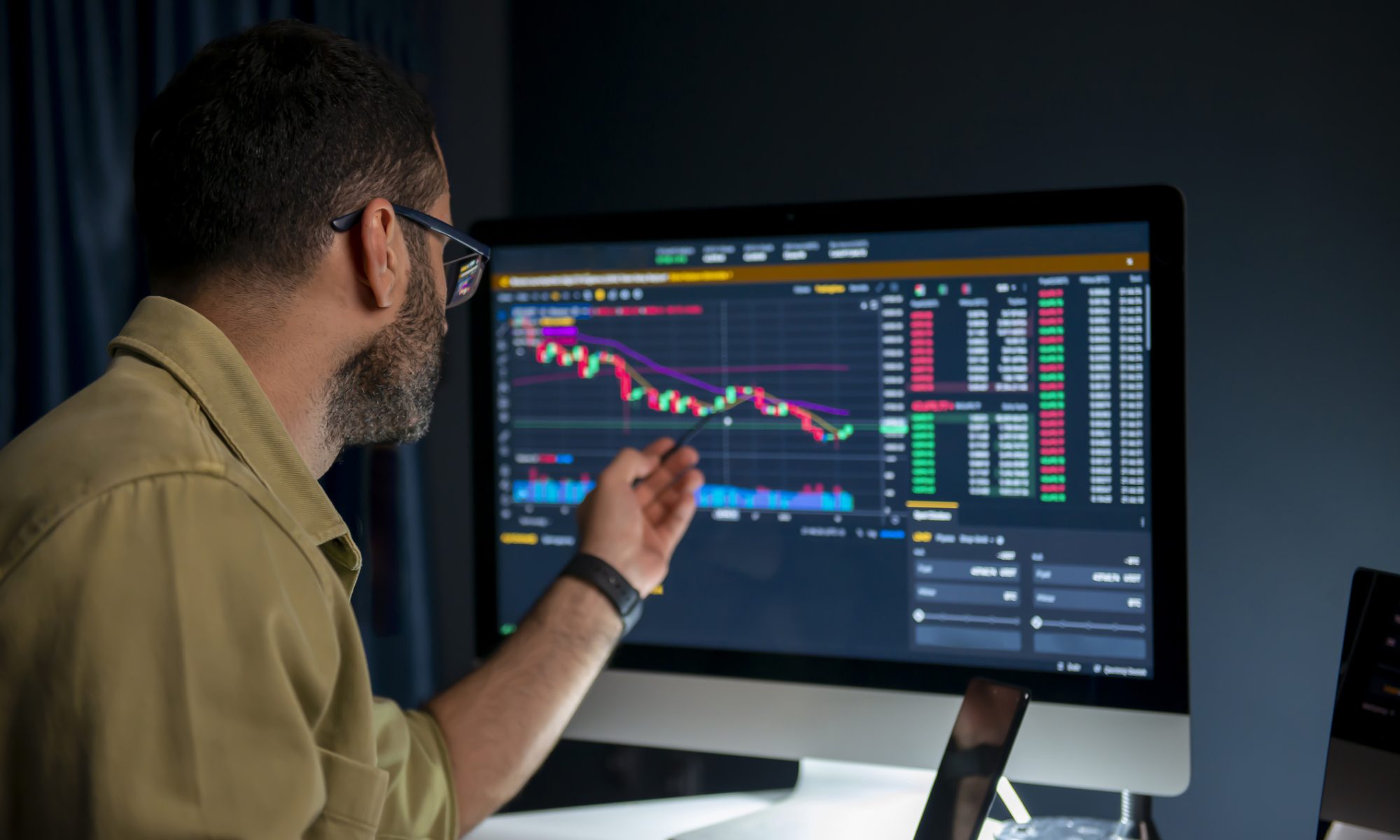Analyst reviewing a falling and then stabilizing stock chart on a desktop trading screen, pointing at candlestick patterns and technical indicators during a market session.
