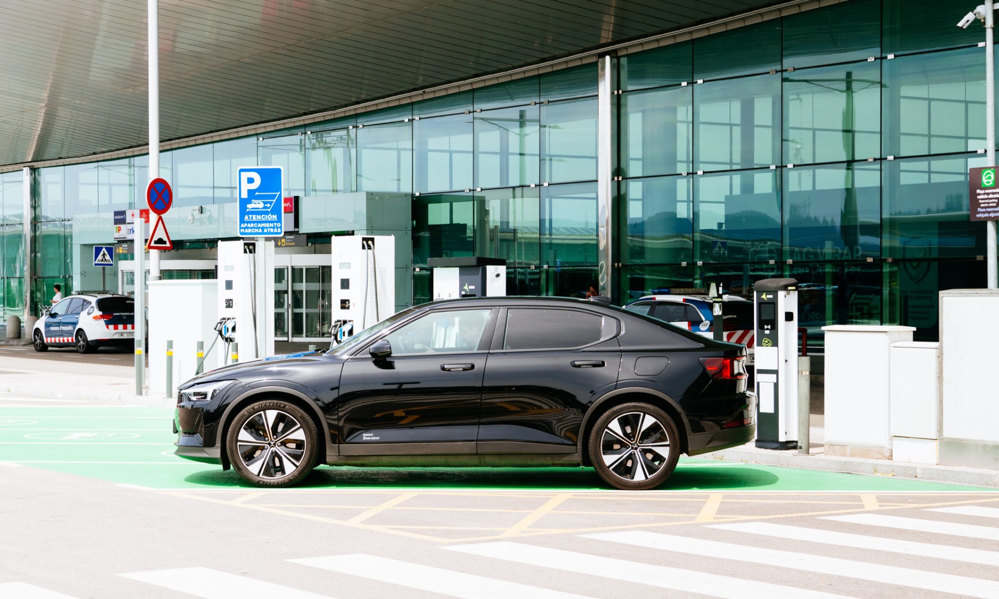 Polestar electric vehicle charging at public EV station outside modern glass facility, highlighting expansion of smart charging infrastructure and energy management technology.