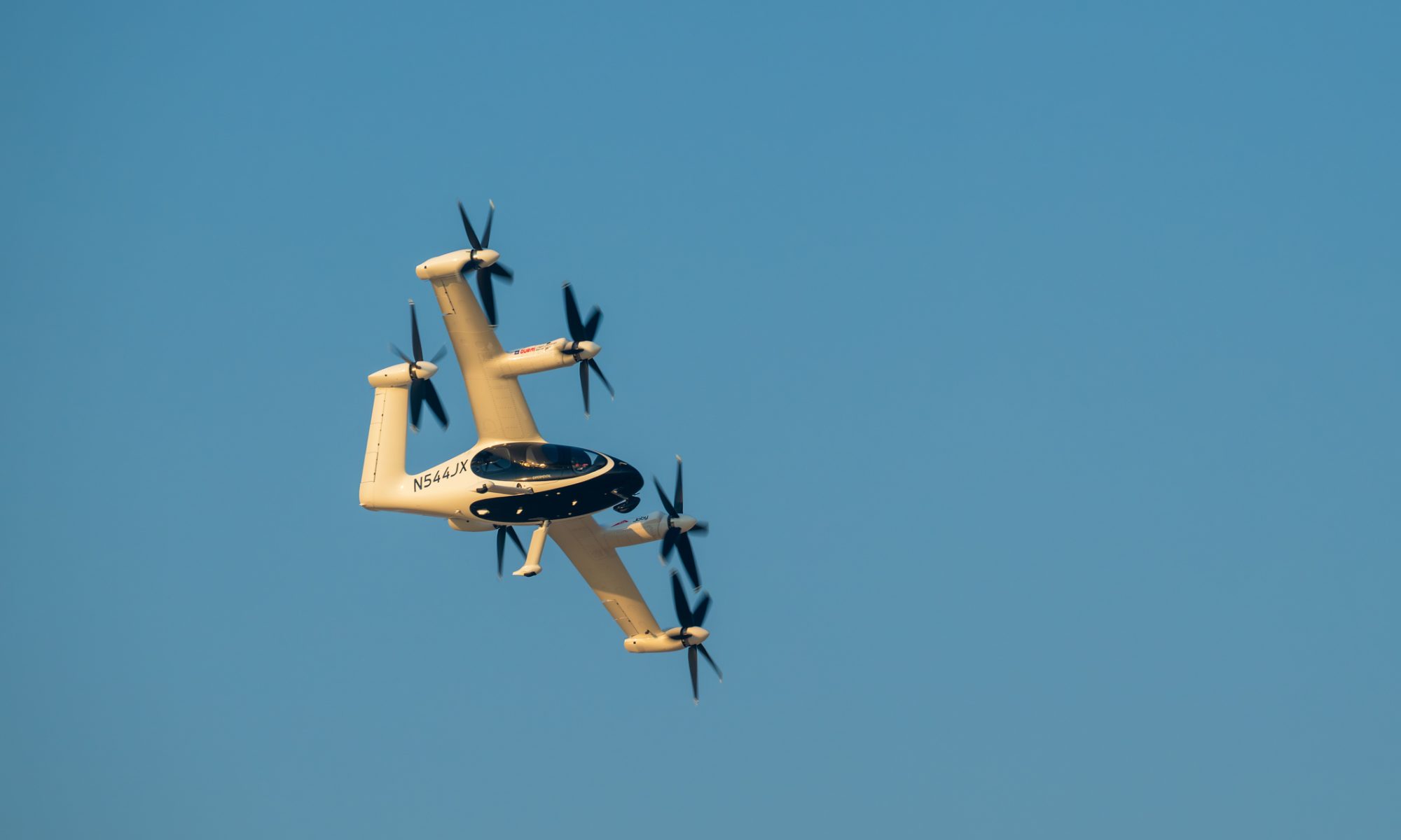 Electric vertical takeoff and landing (eVTOL) aircraft flying against a clear blue sky.