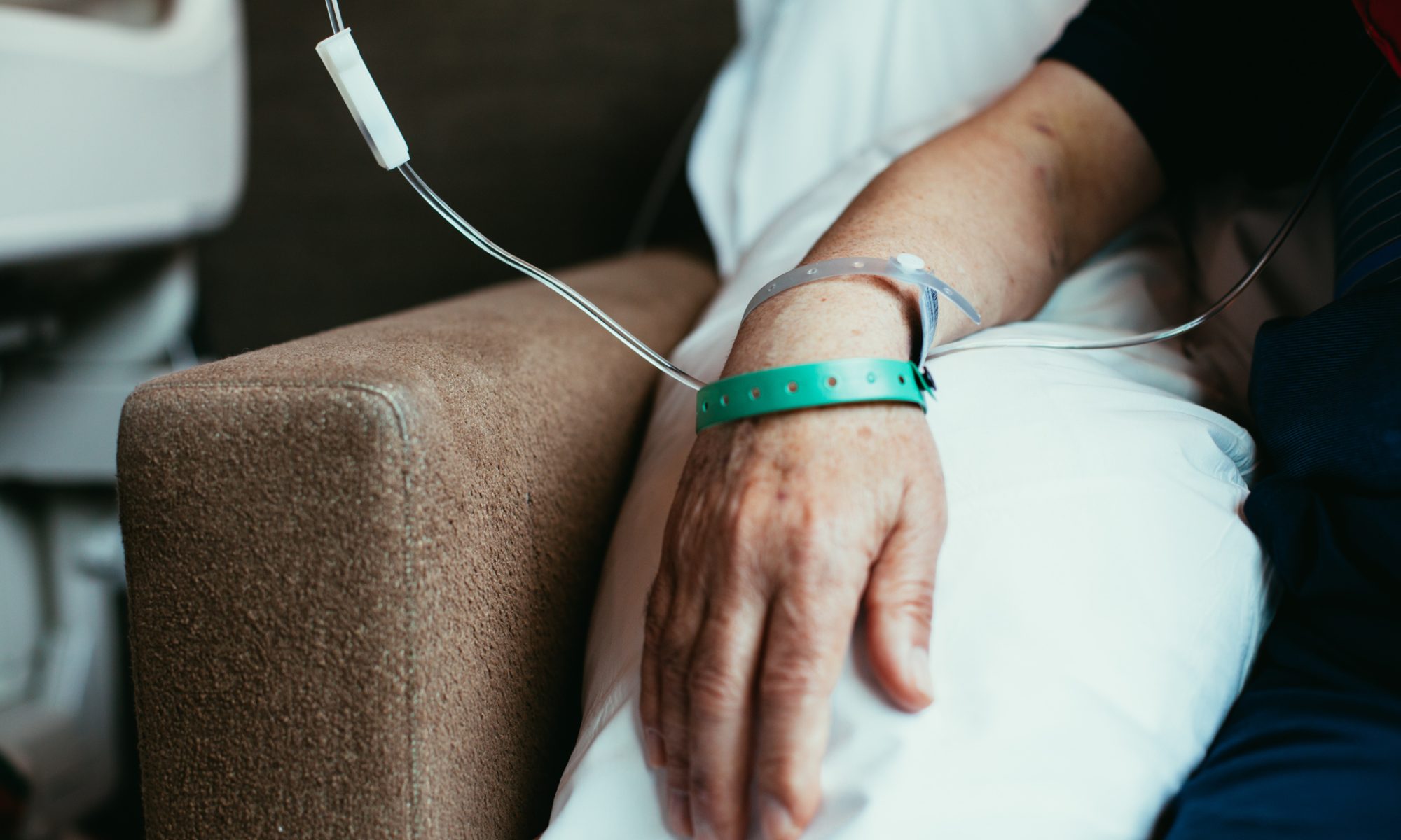 Patient receiving an intravenous infusion in a clinical setting, with a medical line attached to the arm.