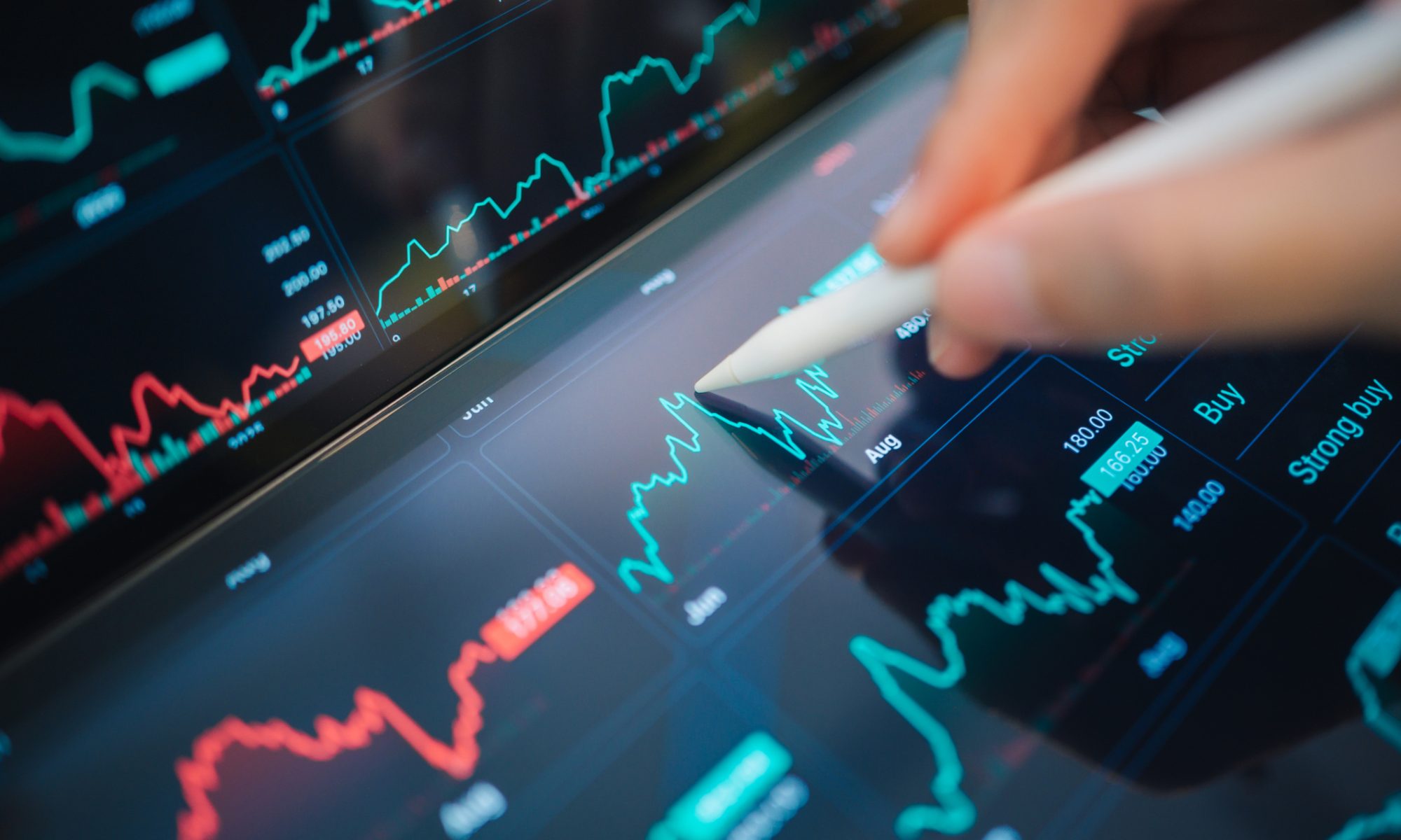 A close-up of a digital stock trading platform shows live market charts and price graphs as a person uses a stylus to analyze market trends and trading activity.
