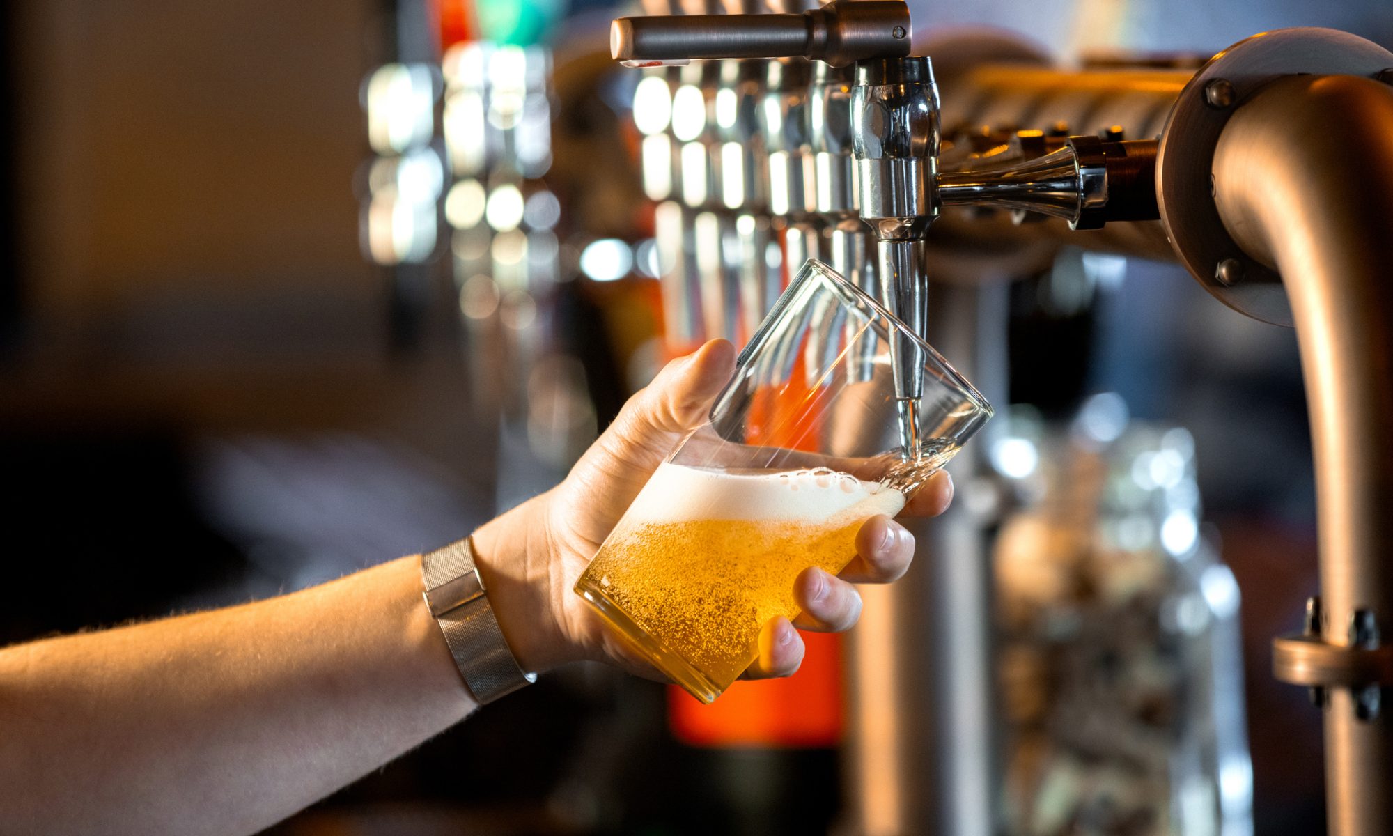 Bartender pours a glass of craft beer from a tap, representing Tilray Brands’ Montauk Brewing collaboration with Morning Brew on a limited-edition coffee-infused blonde ale.