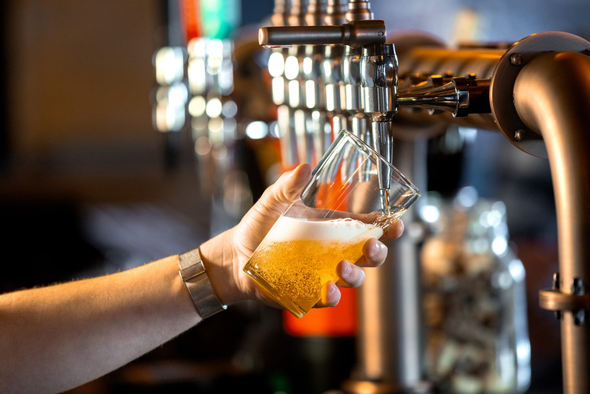 Bartender pours a glass of craft beer from a tap, representing Tilray Brands’ Montauk Brewing collaboration with Morning Brew on a limited-edition coffee-infused blonde ale.
