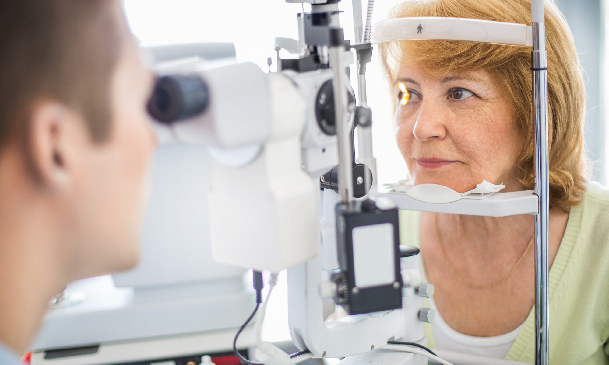 Patient undergoing an eye examination with an ophthalmologist, representing clinical development and competition in long-acting treatments for wet age-related macular degeneration.