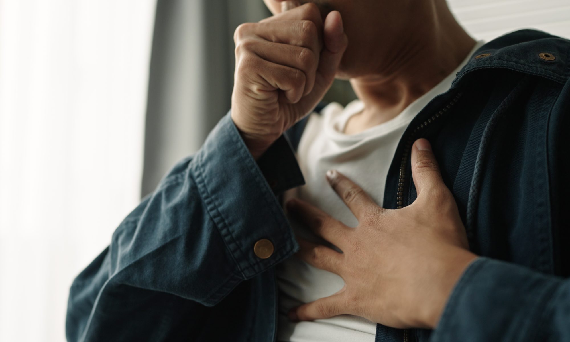 Person coughing and holding their chest, representing lung-health concerns and the potential role of bioAffinity’s CyPath Lung test in evaluating lung-cancer risk.