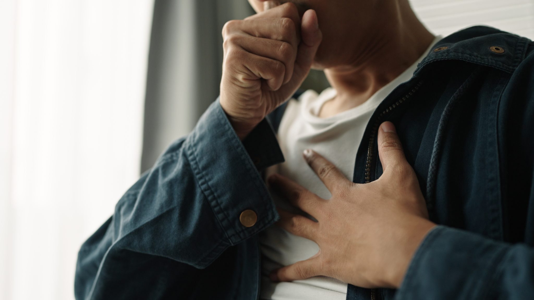 Person coughing and holding their chest, representing lung-health concerns and the potential role of bioAffinity’s CyPath Lung test in evaluating lung-cancer risk.