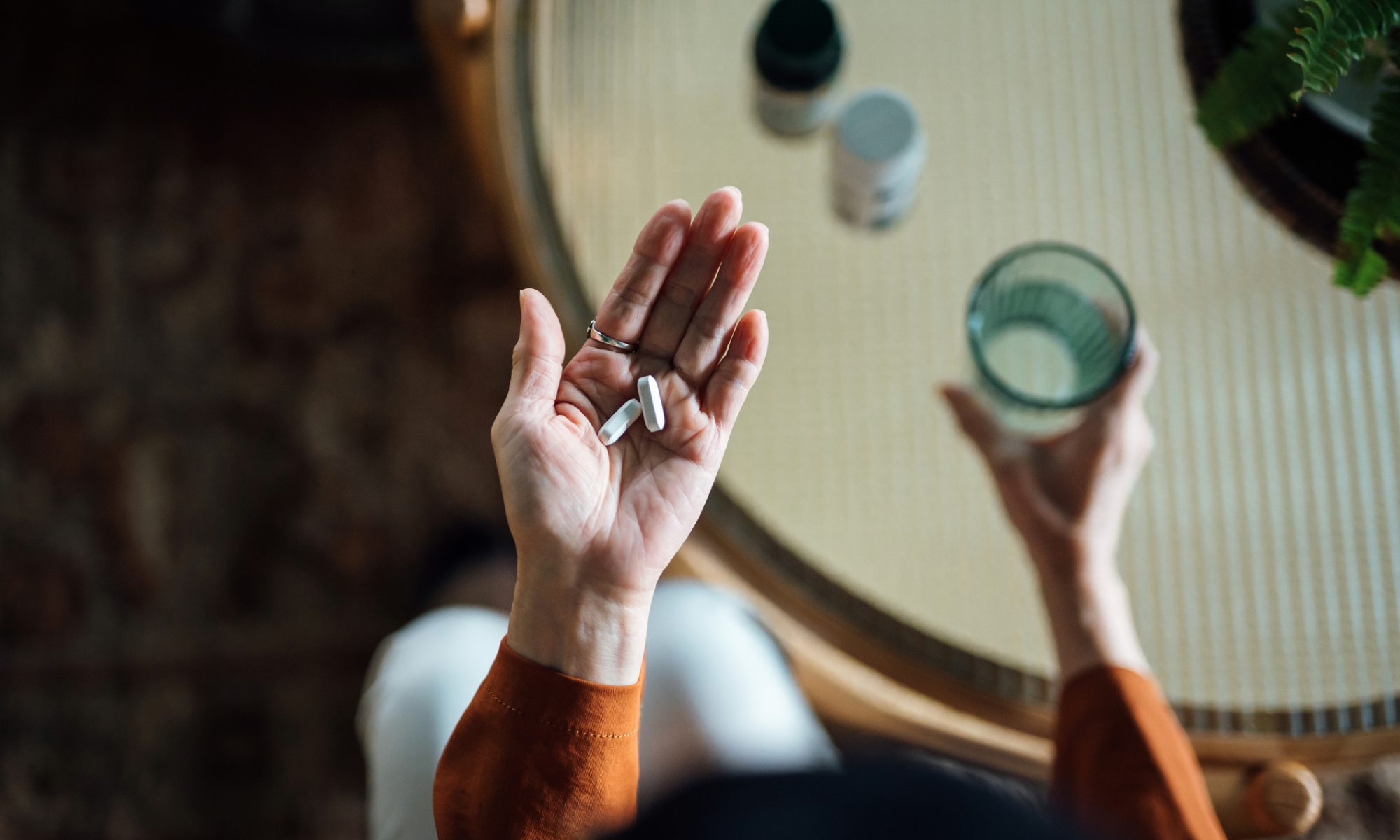 Person holding medication and a glass of water, representing AC Immune’s early clinical development of the oral NLRP3 inhibitor ACI-19764 for inflammation-related conditions.