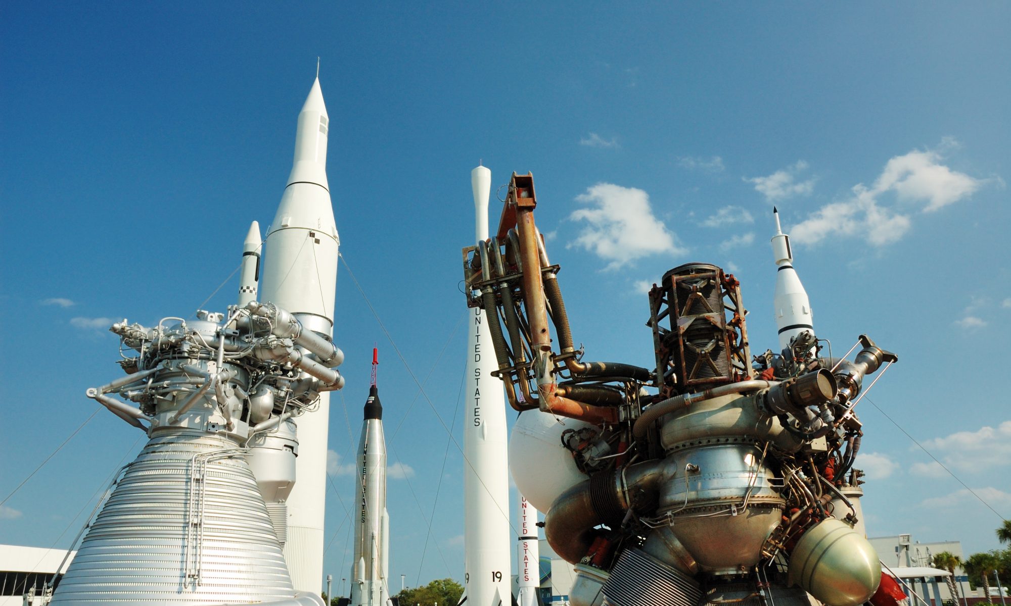 NASA rocket engines and launch vehicles displayed under a blue sky, representing Amentum’s $974 million contract to modernize research infrastructure at NASA’s Langley Research Center.