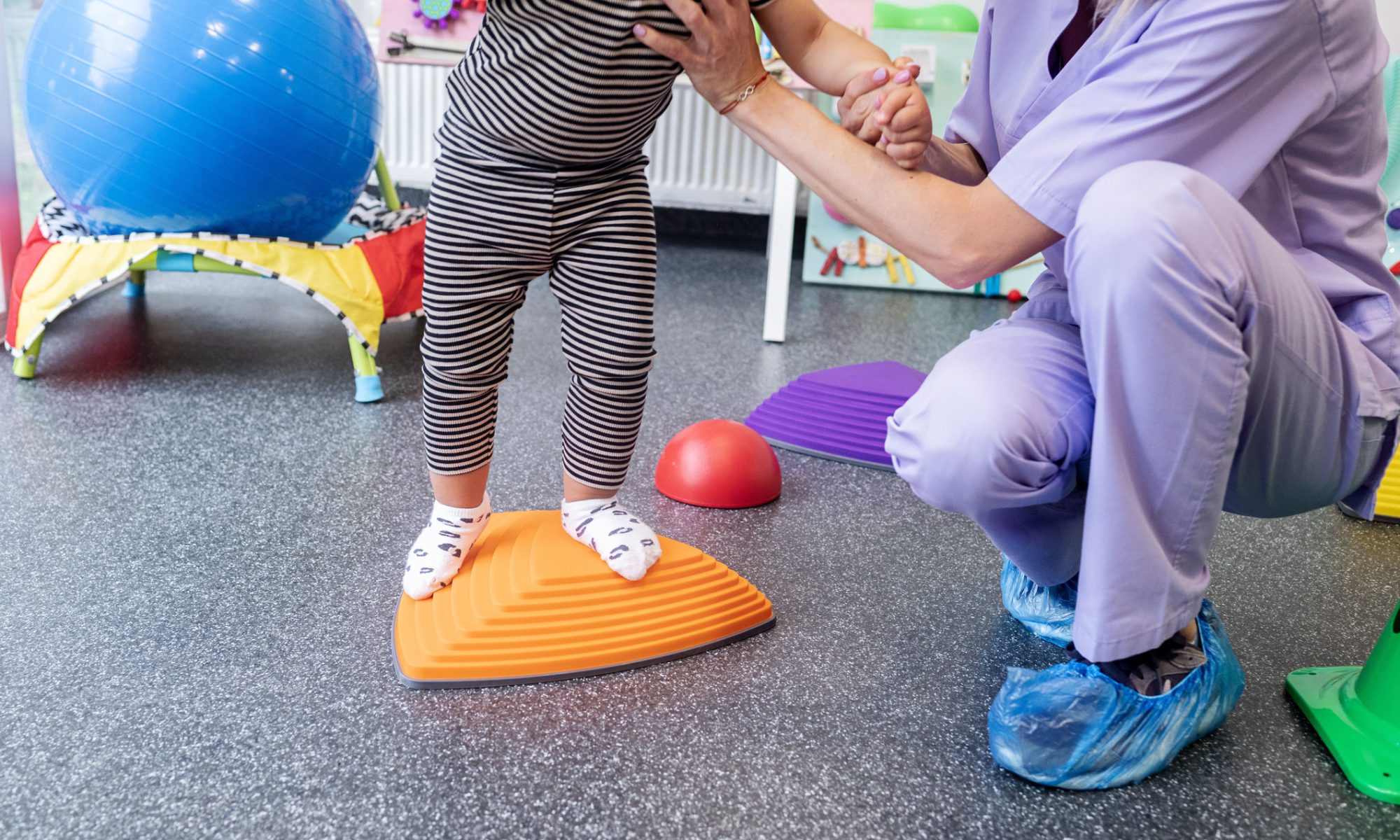 Child participating in a pediatric physical therapy session with assistance from a healthcare professional, illustrating orthopedic care for children with hip and mobility conditions.