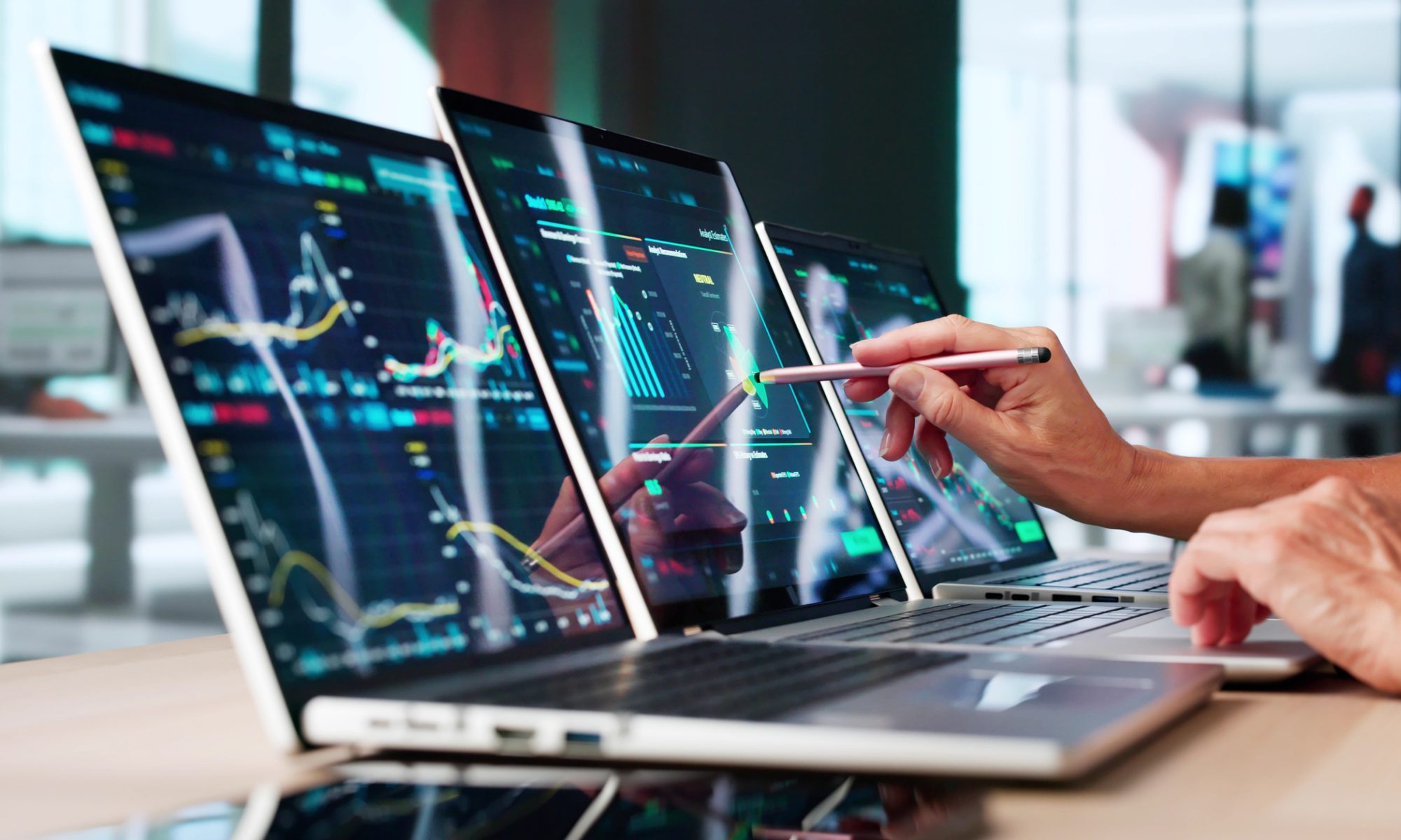 Investor analyzes stock-market charts across multiple computer screens, representing heavy trading activity and volatility among PRISM Mid-Day Movers.
