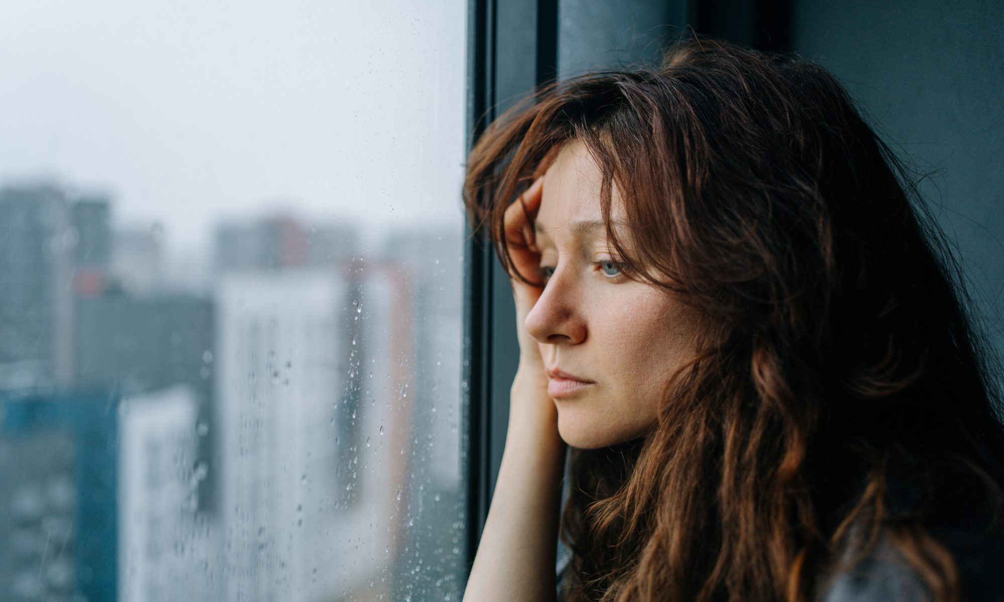 Woman looking out a rain-covered window, representing major depressive disorder and the development of new treatments for depression.