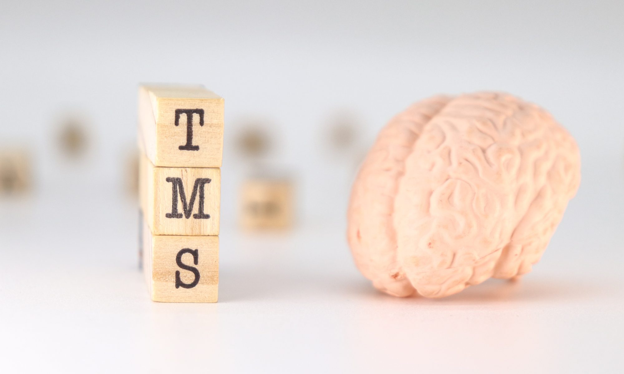 Model of a human brain beside wooden TMS blocks, representing BrainsWay’s Deep TMS research in patients with depression and early-stage Alzheimer’s disease.
