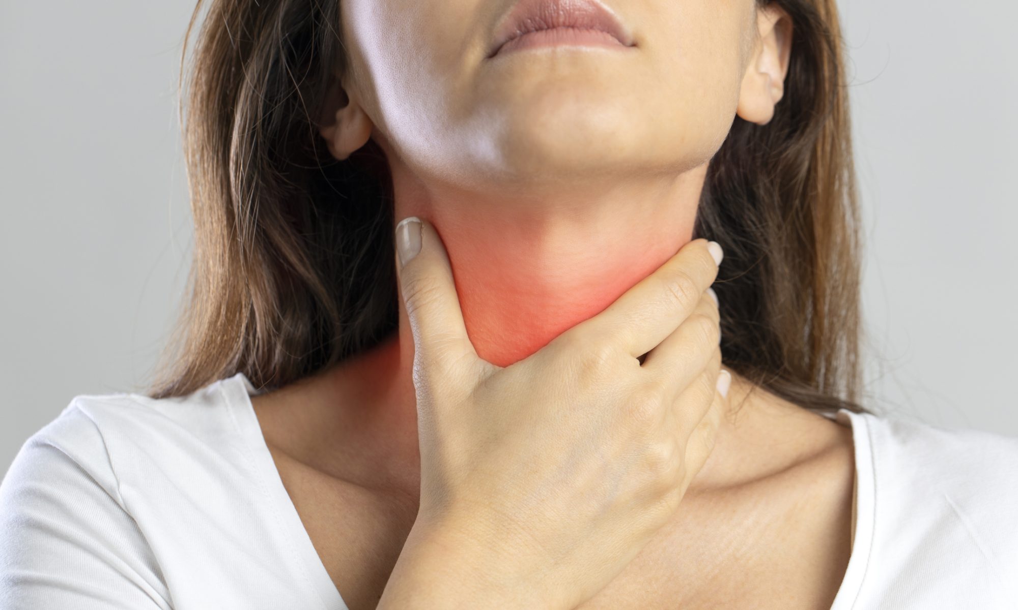 Woman holding her neck with a red highlighted area around the thyroid, representing thyroid discomfort and treatment for symptomatic benign thyroid nodules.