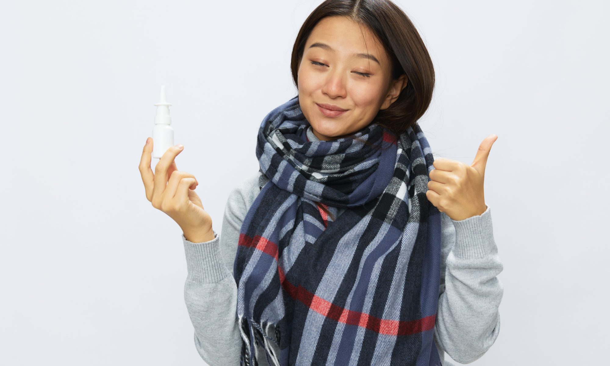 Woman holding a nasal spray bottle, representing Vistagen’s investigational fasedienol treatment for social anxiety disorder.