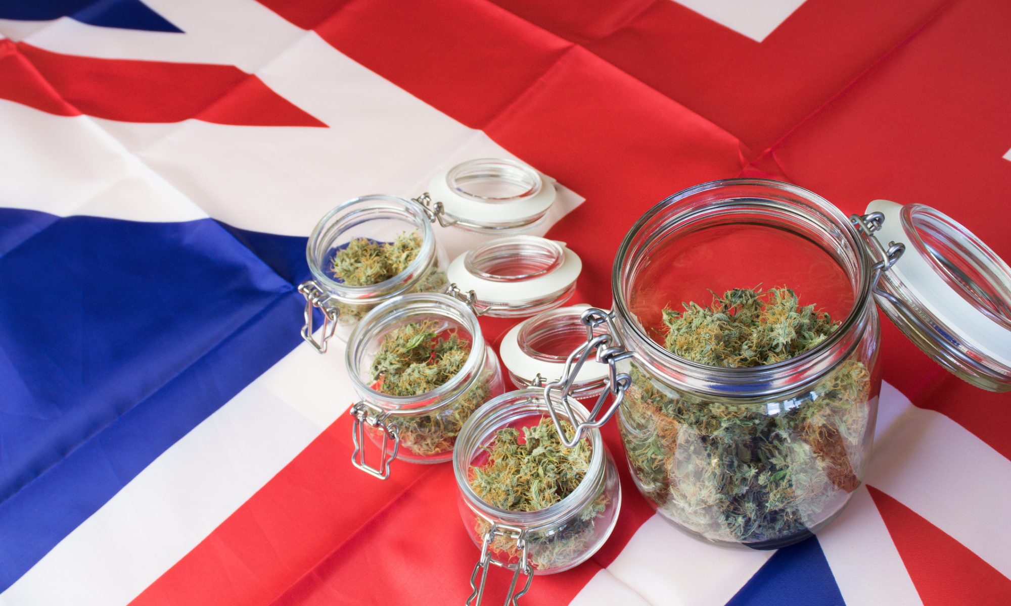 Glass jars filled with cannabis flower arranged on a British flag, representing Canopy Growth’s expansion of Canadian medical cannabis products into the UK market.