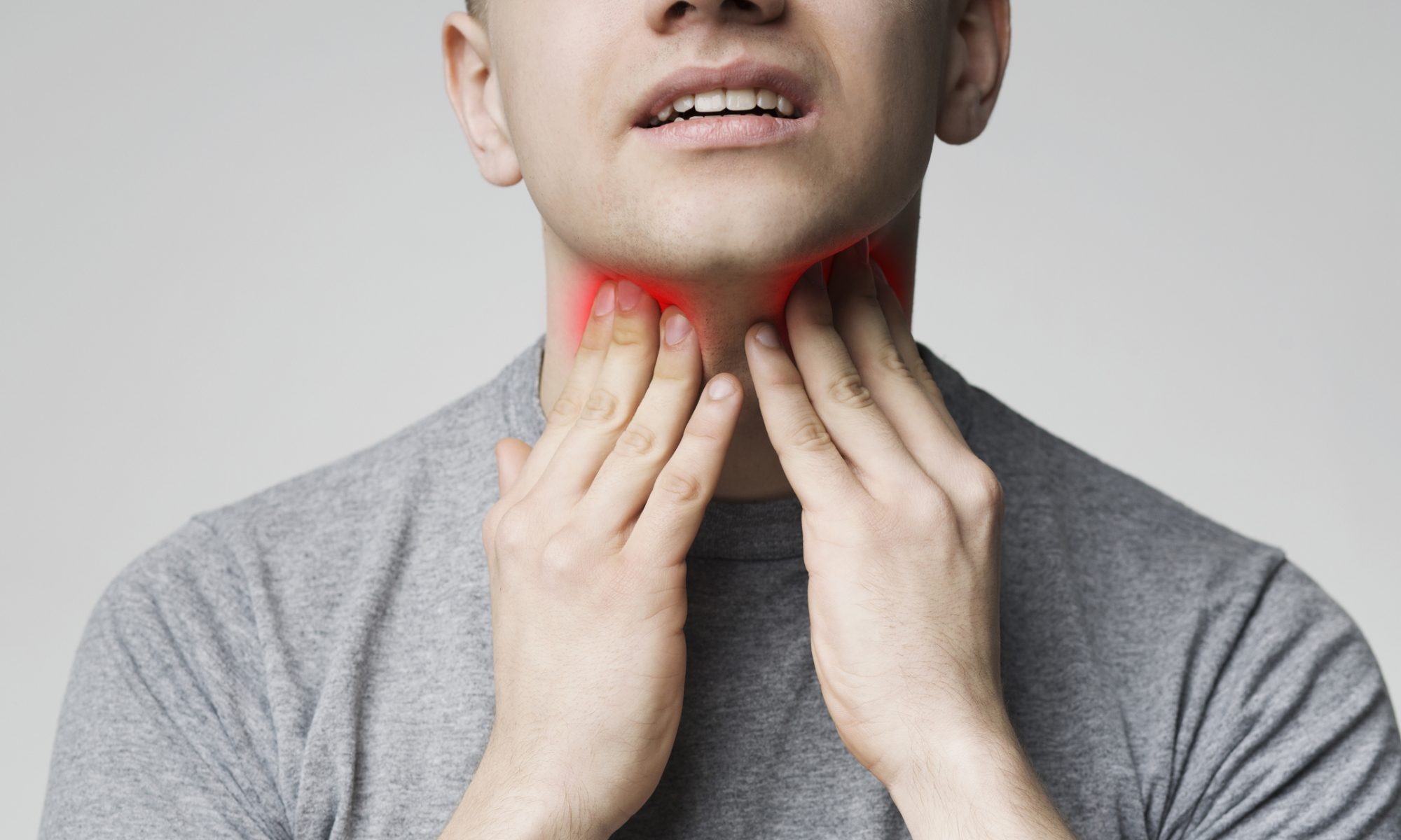 Man touching both sides of his neck with a highlighted throat area, representing treatment research for oropharyngeal cancer.