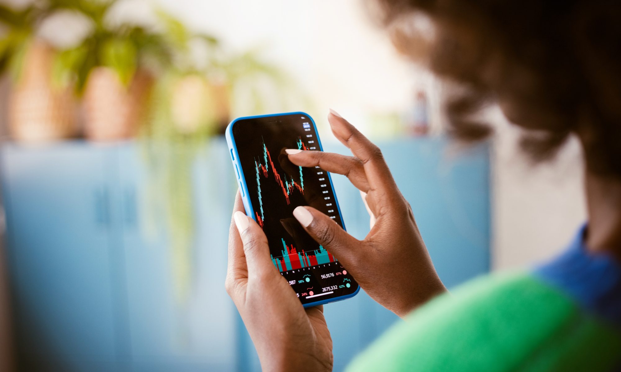 Investor viewing a stock market chart on a smartphone, representing active trading and sharp midday moves in EV and healthcare stocks.