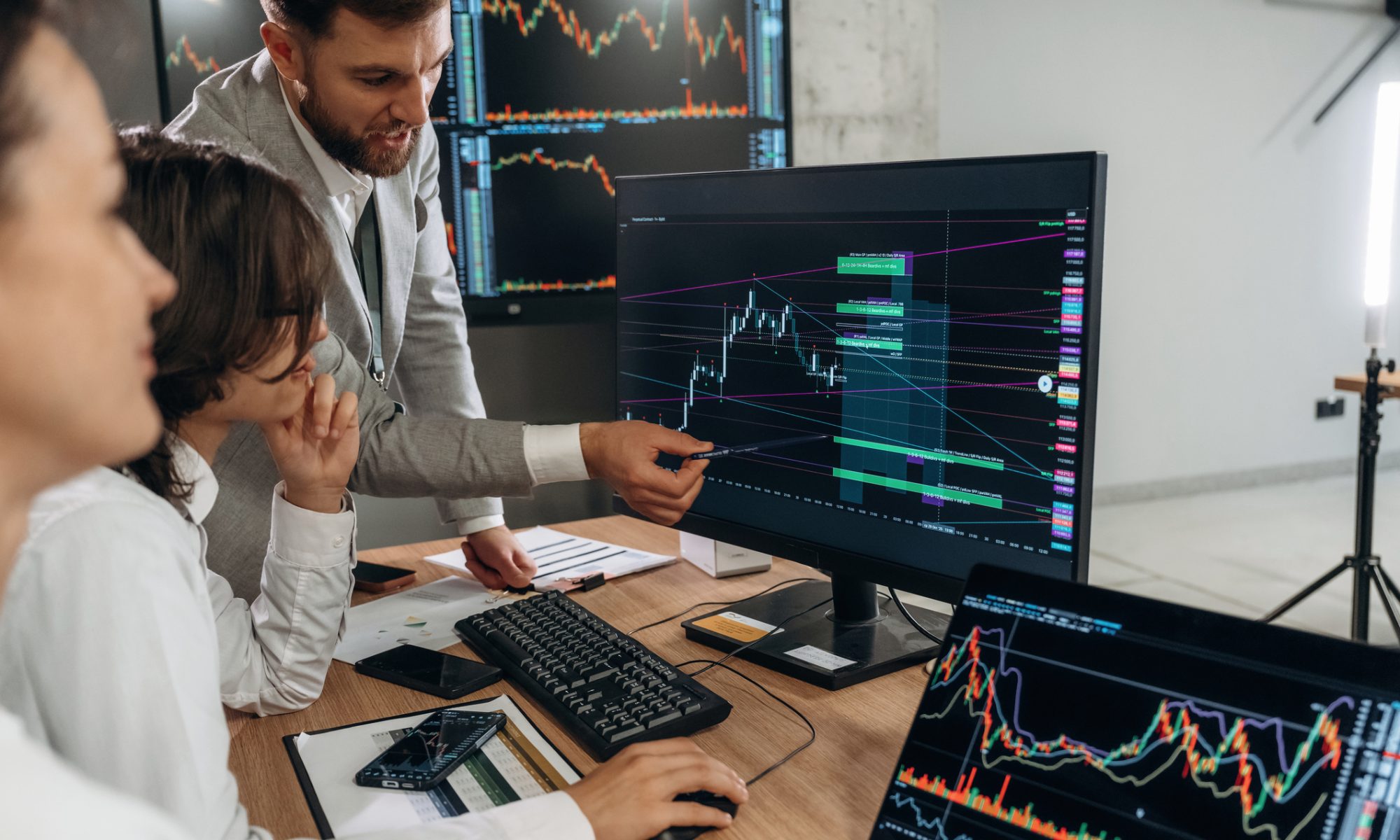 Market analysts review stock charts and trading data on multiple monitors, representing active midday trading and market movers.