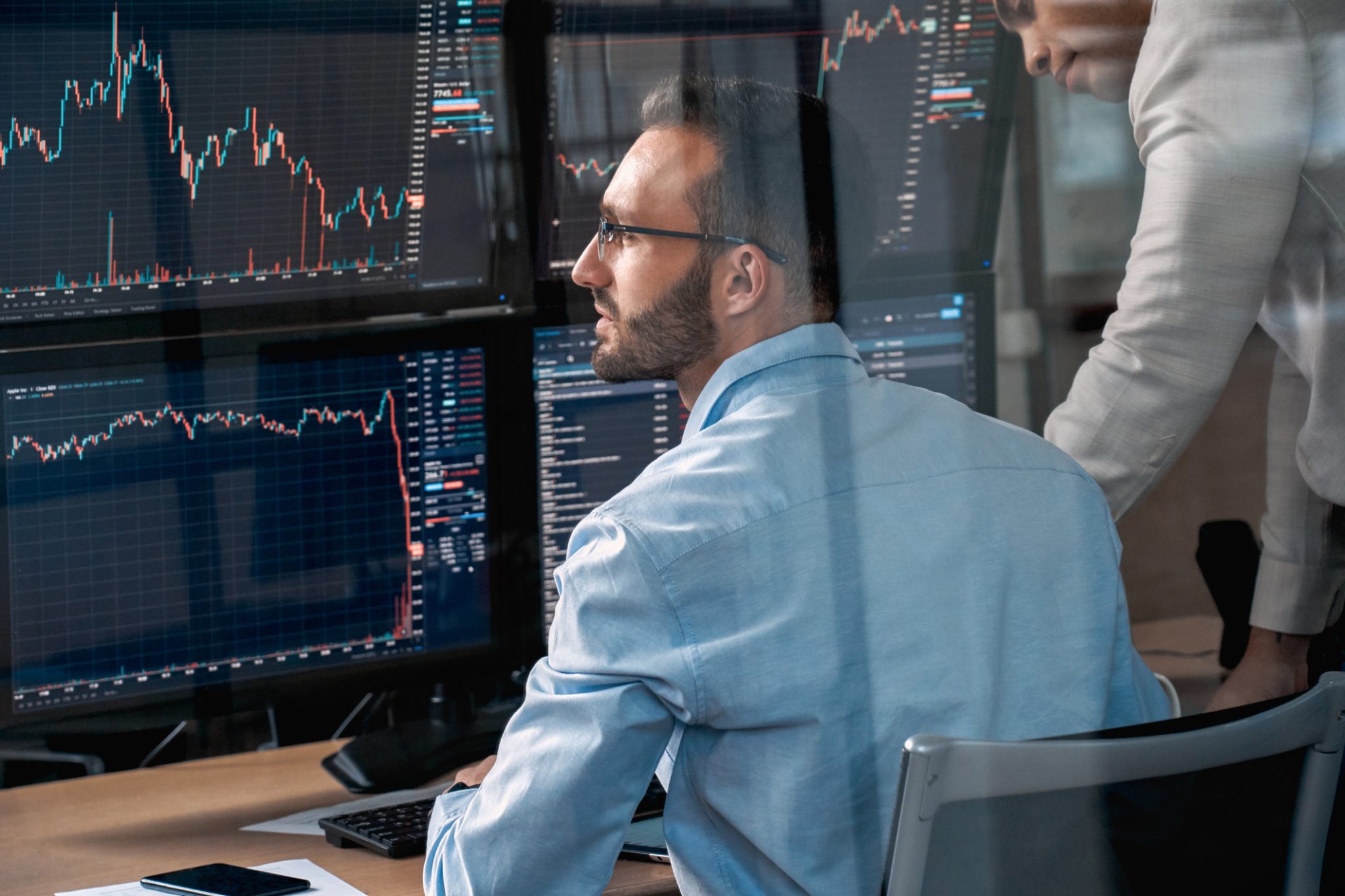 Financial professionals monitor multiple stock-market charts and trading screens, representing active midday market movers.