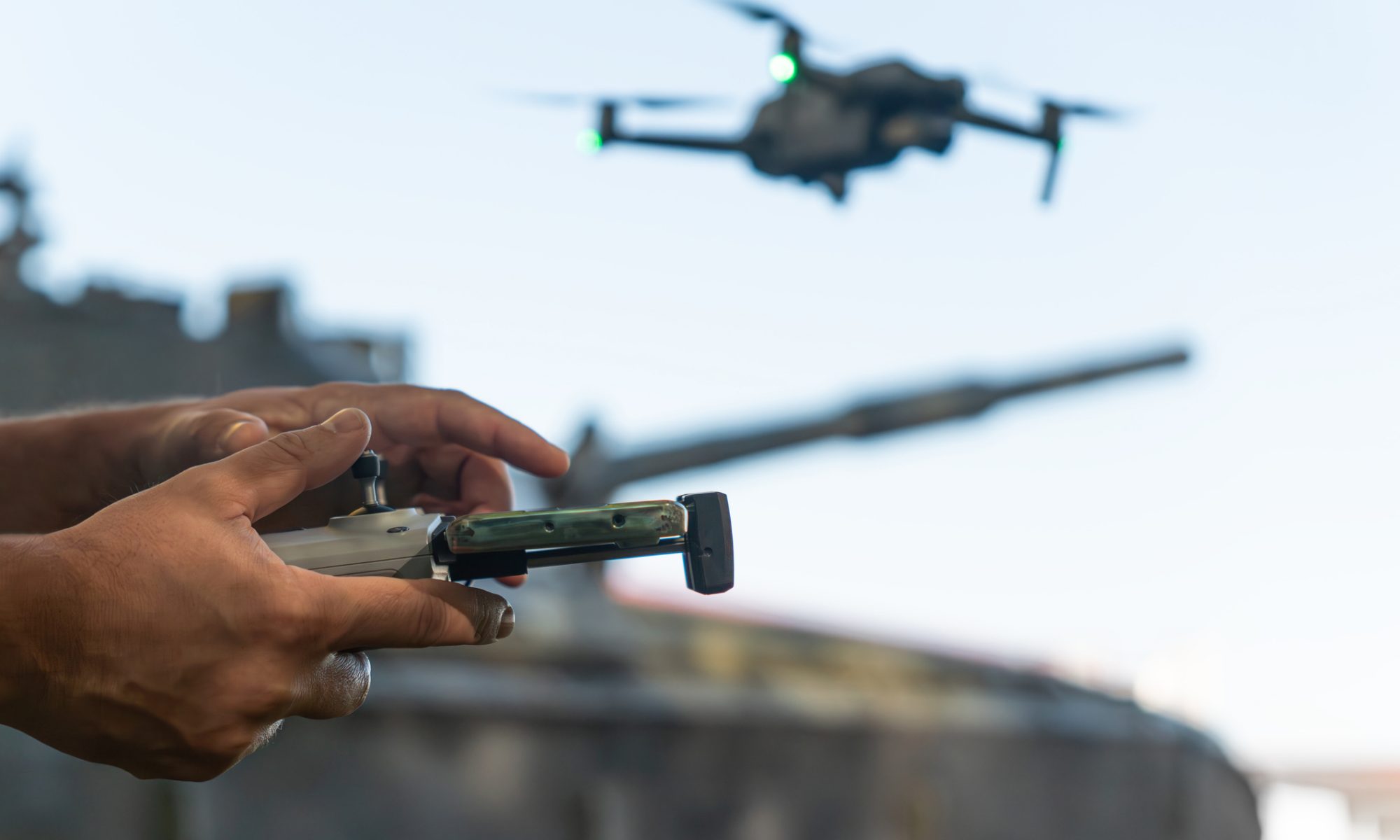 Operator controls a drone near a military vehicle, illustrating autonomous robotics and real-time mission technology.