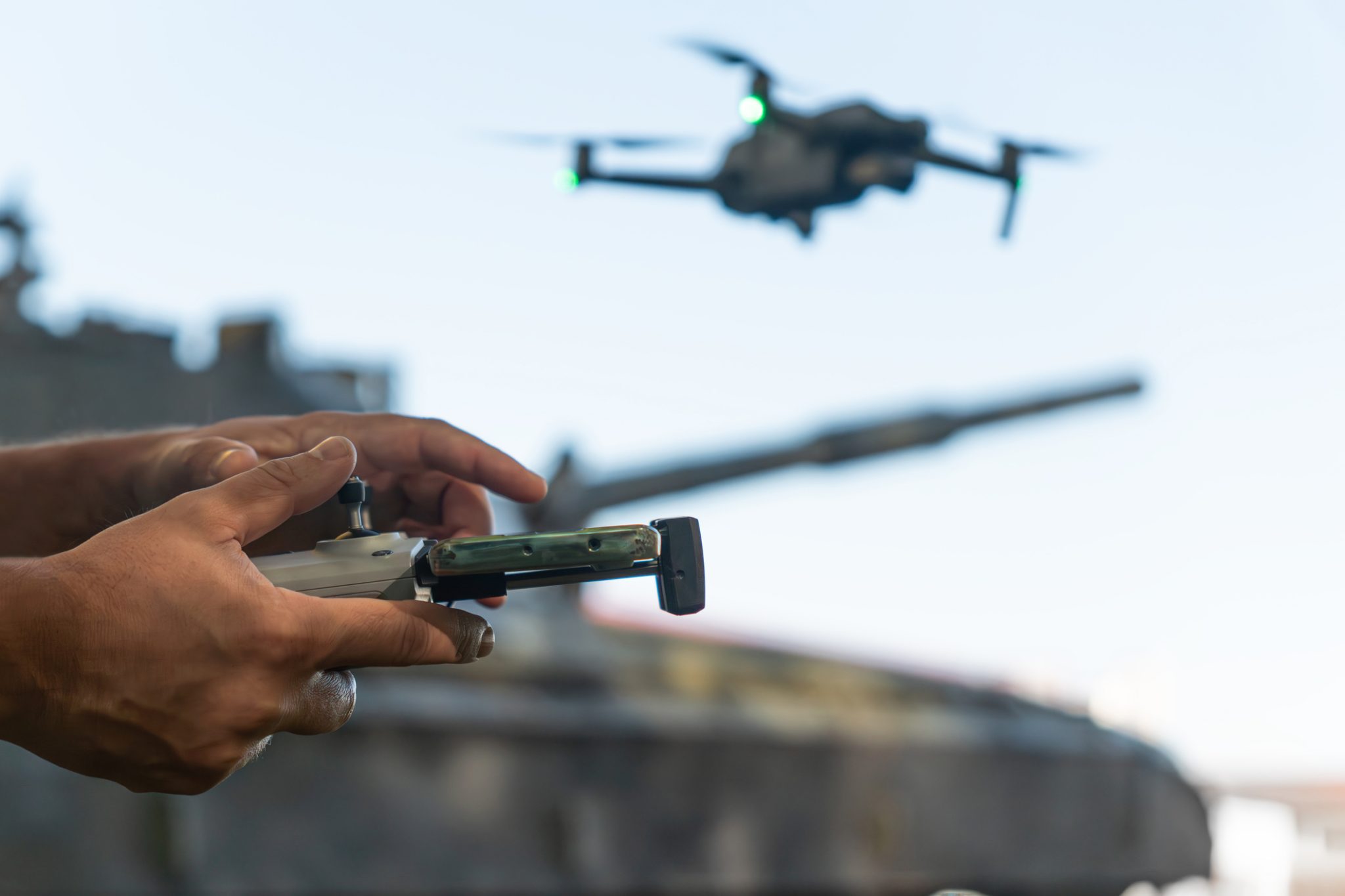 Operator controls a drone near a military vehicle, illustrating autonomous robotics and real-time mission technology.