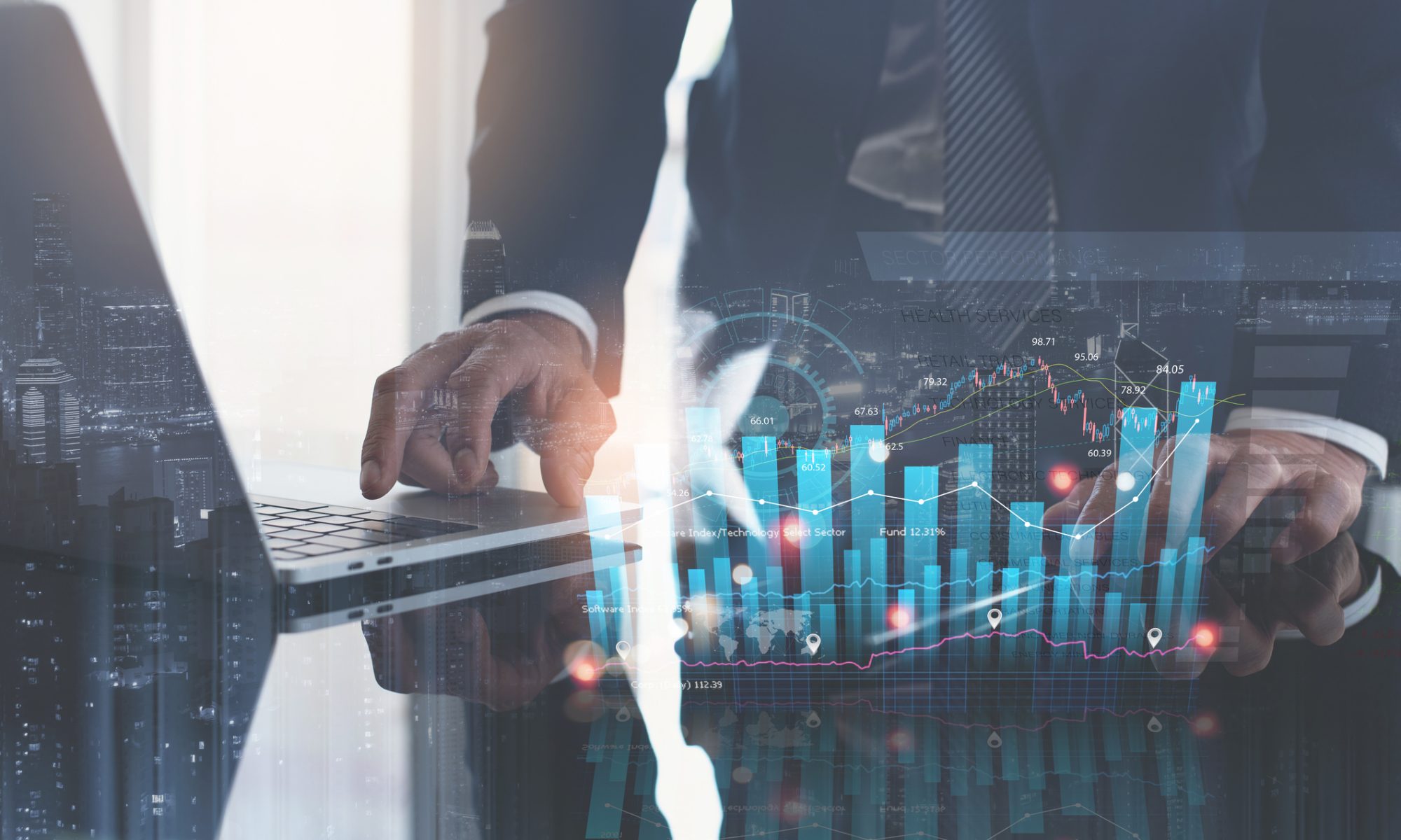 Business professional analyzes financial market charts and stock performance data on a laptop and digital display.