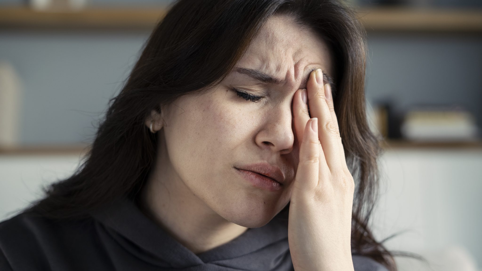 Woman experiencing eye pain holds her hand against her eye, representing neuropathic corneal pain and ocular discomfort.