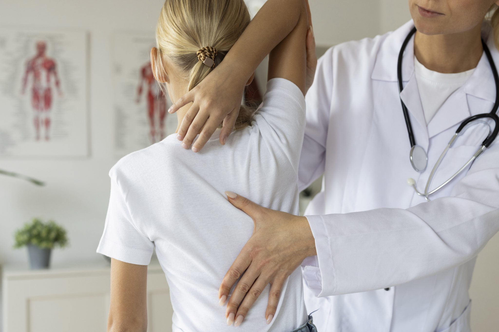 Healthcare professional examines a patient’s shoulder and upper back during a musculoskeletal assessment.