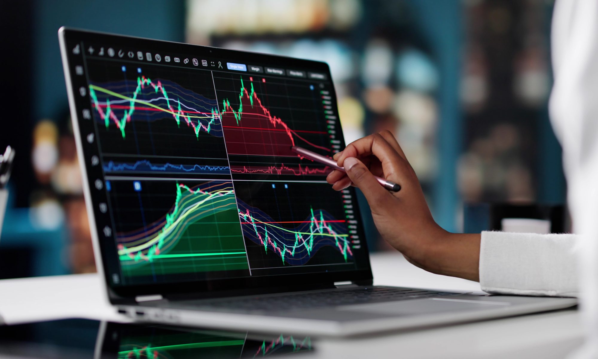 Investor analyzing stock market charts on a laptop, using a stylus to examine trading trends and price movements.