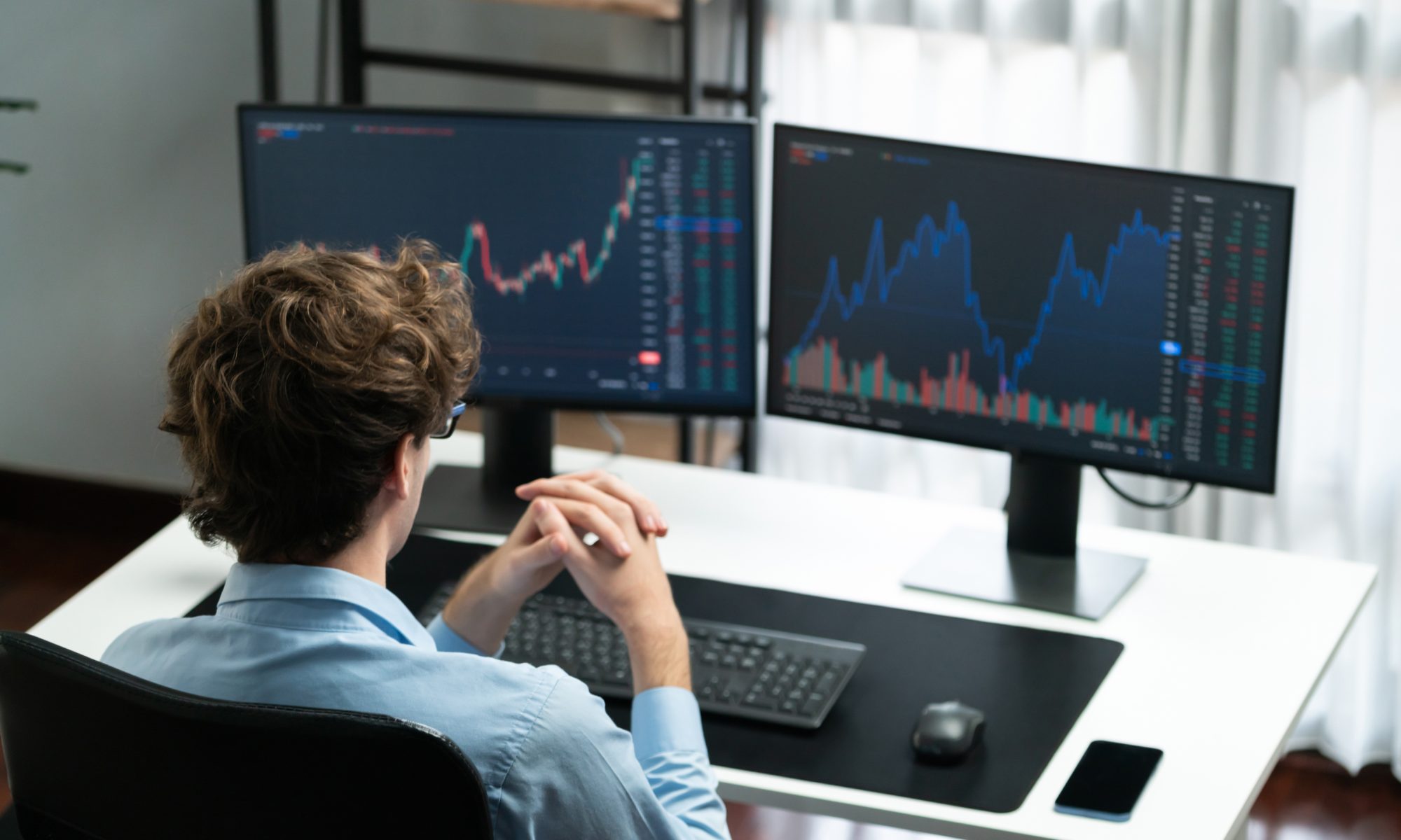 Stock market trader monitors financial charts and trading activity on dual computer screens, illustrating midday stock market movements and investor analysis.