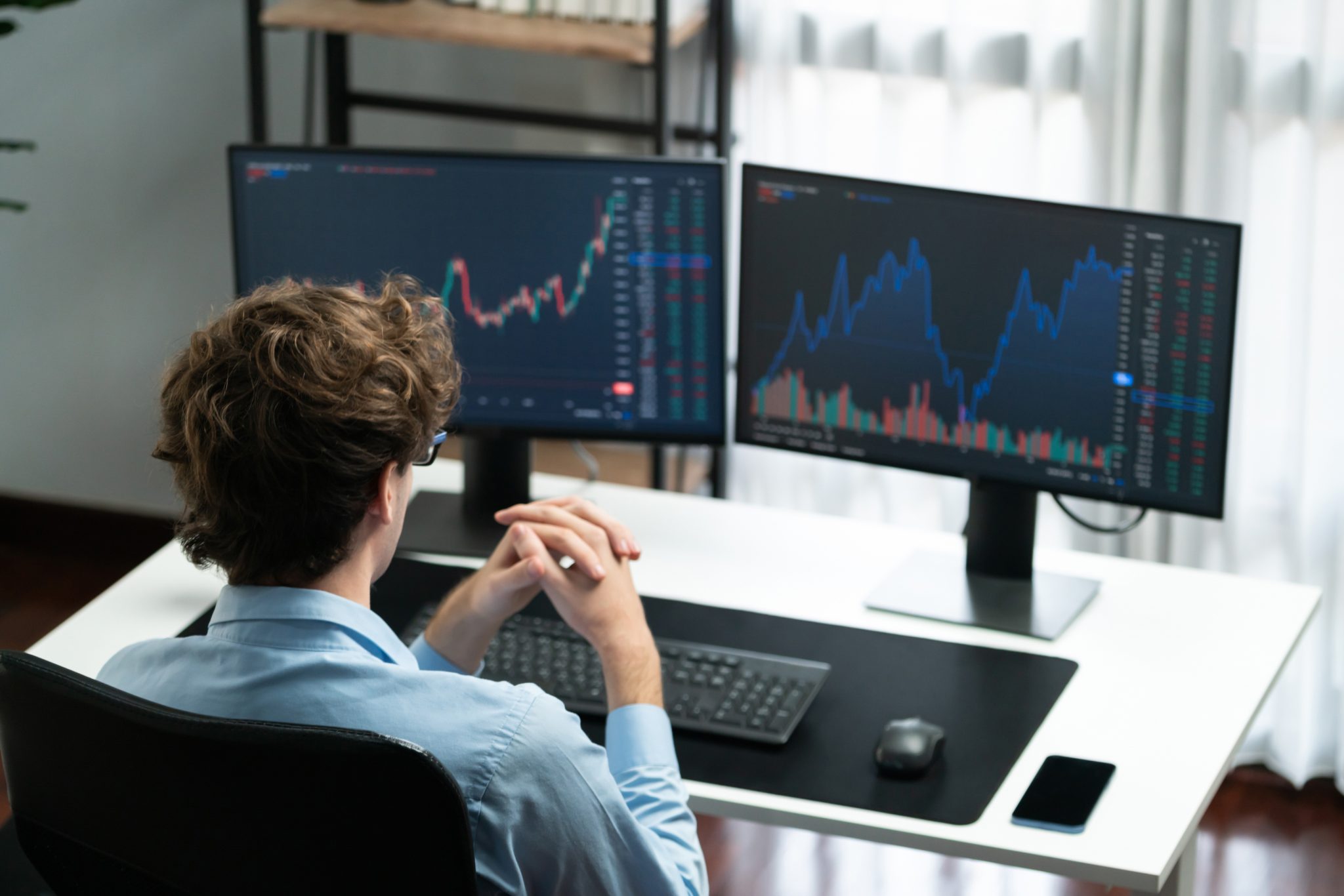 Stock market trader monitors financial charts and trading activity on dual computer screens, illustrating midday stock market movements and investor analysis.