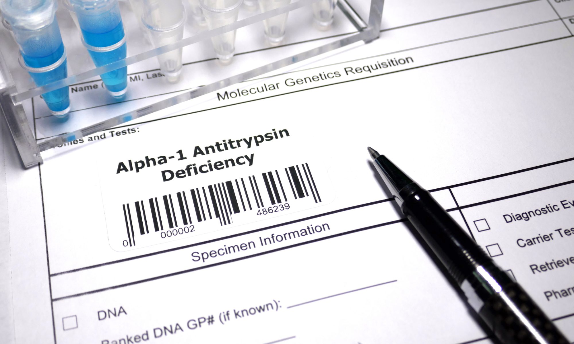 Close-up of a molecular genetics testing form labeled Alpha-1 Antitrypsin Deficiency, alongside laboratory sample tubes and a pen, illustrating genetic research and testing for AATD.